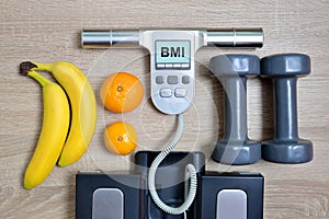 Body Mass Index Scale with fruits and dumbbells on wooden board.