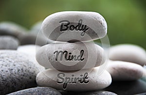 Body, Mind and Spirit words engraved on zen stones. Copy space and zen concept