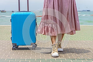 Body part of female tourist and modern blue rolling hard baggage.