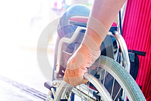 Body part,Hand man and wheelchair.Disabled man is sitting on wheelchair and holding wheel.He is driving on road.