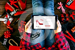 Body part of woman female adult buying new red high heels on internet online store shop with tablet during black friday holiday