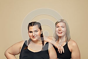 Body Positive. Plus Size Models Portrait. Full-Figured Women In Sportswear On Beige Background.