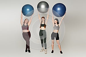 Body positive sportswomen holding fitness balls