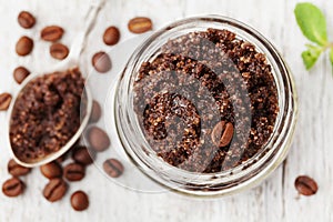 Body scrub of ground coffee, sugar and coconut oil in glass jar on white rustic table, homemade cosmetic for peeling and spa