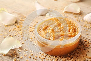 Body scrub, petals and sugar on wooden background