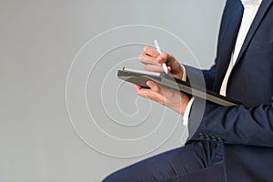 Body shot of business man in suit sitting and working with digital tablet