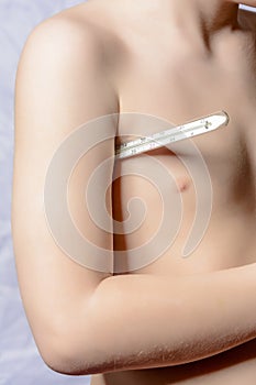 The body of a small boy, who holds a thermometer at hand and measures the body