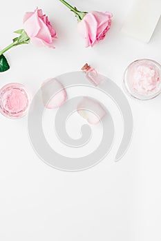 Body treatment with rose flowers and cosmetic set white desk background top view space for text