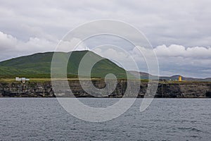 Body of water with mountains in the distance against a cloudy sky in Husavik
