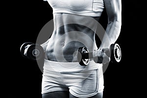 Body of a young fit woman lifting dumbbells