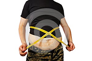 Body of young man with excess weight, keep belly fat in a T shirt, measure itself with a measuring tape. isolated on white