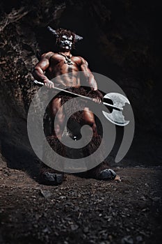 The bodyart man angry minotaur with axe in cave