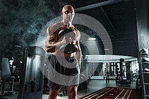 Bodybuilder athlete trains in the gym. Sporty muscular guy with barbell. Sport and fitness motivation. Individual sports