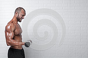 Bodybuilder doing exercises for biceps with a dumbbells against