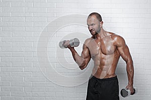 Bodybuilder doing exercises for biceps with a dumbbells against