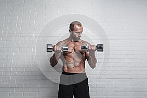 Bodybuilder doing exercises for biceps with a dumbbells against