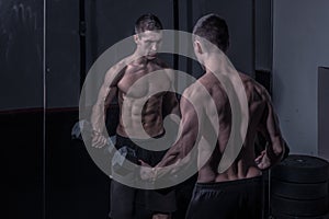 Bodybuilder, looking at himself, holding dumbbells