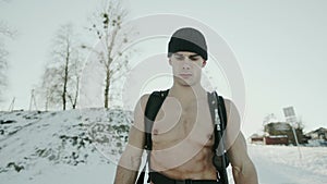 Bodybuilder with a naked torso with a ballon compressed air drager on his back goes through a snowy glade against the