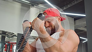 Bodybuilder performs exercise in biceps simulator in the gym. Sports training