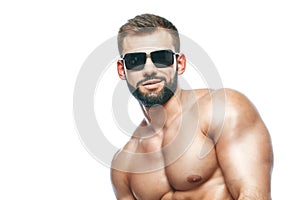 .bodybuilder posing. Beautiful sporty guy male power. Fitness muscled in blue shorts and sunglasses. on isolated white