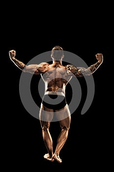 Bodybuilder posing. Beautiful sporty guy male power. Fitness muscular body. Isolated on black background
