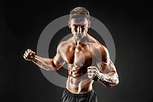 Bodybuilder posing. Fitness muscled man on dark background.