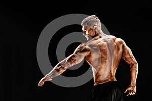 Bodybuilder posing. Fitness muscled man on dark background.