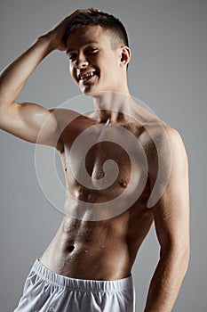 bodybuilder with a pumped up torso in white shorts on a gray background cropped view