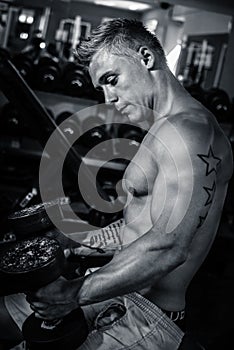 Bodybuilder sitting with weights in the gym