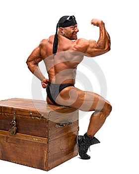 Bodybuilder sitting on a wooden chest