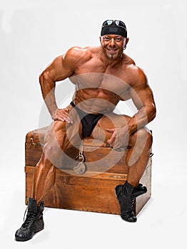 Bodybuilder sitting on a wooden chest