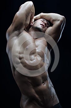 Bodybuilder and strip theme: beautiful with pumped muscles naked man posing in the studio on a dark background