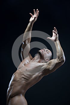 Bodybuilder and strip theme: beautiful with pumped muscles naked man posing in the studio on a dark background