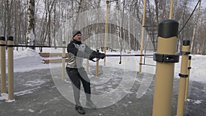 Bodybuilder training anaerobic exercise with expander on outdoor winter training