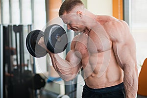 Bodybuilder at well-equipped gym lifting heavy dumbbells.