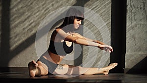 Bodybuilder woman is stretching legs muscles in a gymnastic hall