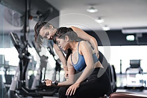 Bodybuilder of women training with dumbbell exercise workout at fitness gym in sportswear with personal trainer coaching