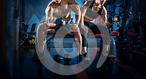 Bodybuilder working out with dumbbell weights at the gym. Young couple is working out at gym. Attractive woman and handsome photo