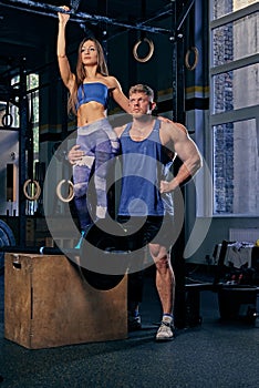 Bodybuilders couple posing near cross fit stand.