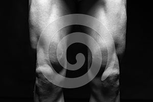 bodybuilders legs. Naked muscular male part in the Dark