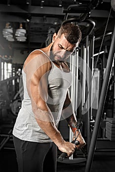 Bodybuilding. Bearded man standing doingcable straight arm pulldown at gym concentrated