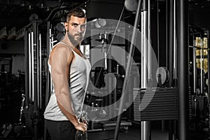 Bodybuilding. Bearded man standing doingcable straight arm pulldown at gym looking camera confident