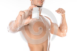 Bodybuilding and chemical additives: handsome strong bodybuilder holding a white jar of pills on white isolated background in stud
