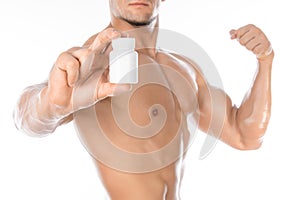 Bodybuilding and chemical additives: handsome strong bodybuilder holding a white jar of pills on white isolated background in stud