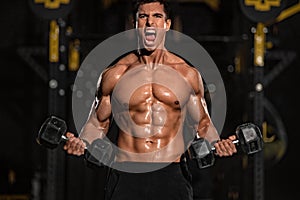 Bodybuilding concept. Brutal strong muscular bodybuilder athletic man pumping up muscles with barbell on black