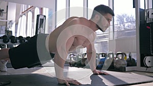 Bodybuilding, muscular athlete man with beautiful sports body does pushups during strength workout at gym