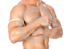 Bodybuilding and Sports theme: handsome strong bodybuilder holding centimeter tape to measure body isolated on white background in