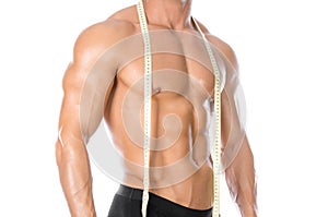 Bodybuilding and Sports theme: handsome strong bodybuilder holding centimeter tape to measure body isolated on white background in