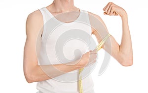 Bodybuilding and Sports theme: a thin man in a white T-shirt and jeans with measuring tape isolated on a white background in studi