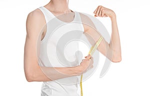 Bodybuilding and Sports theme: a thin man in a white T-shirt and jeans with measuring tape isolated on a white background in studi